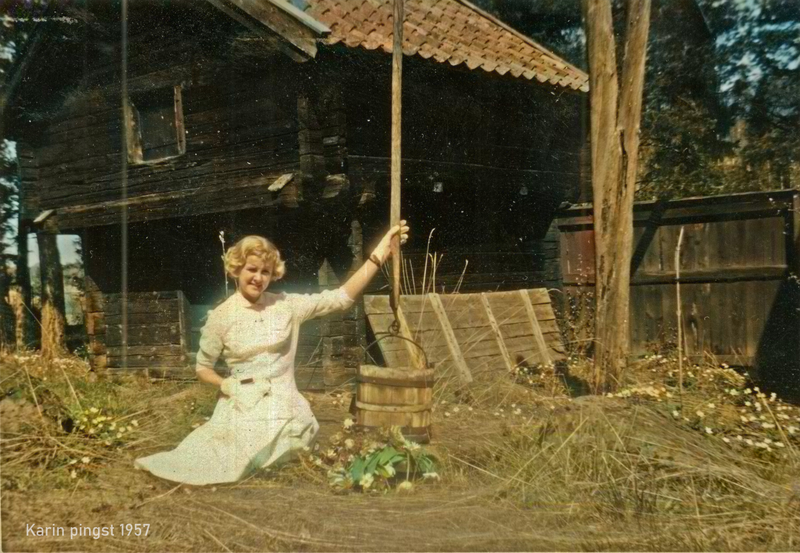 Karin sitter i gräset vid gammelgården pingsten 1957